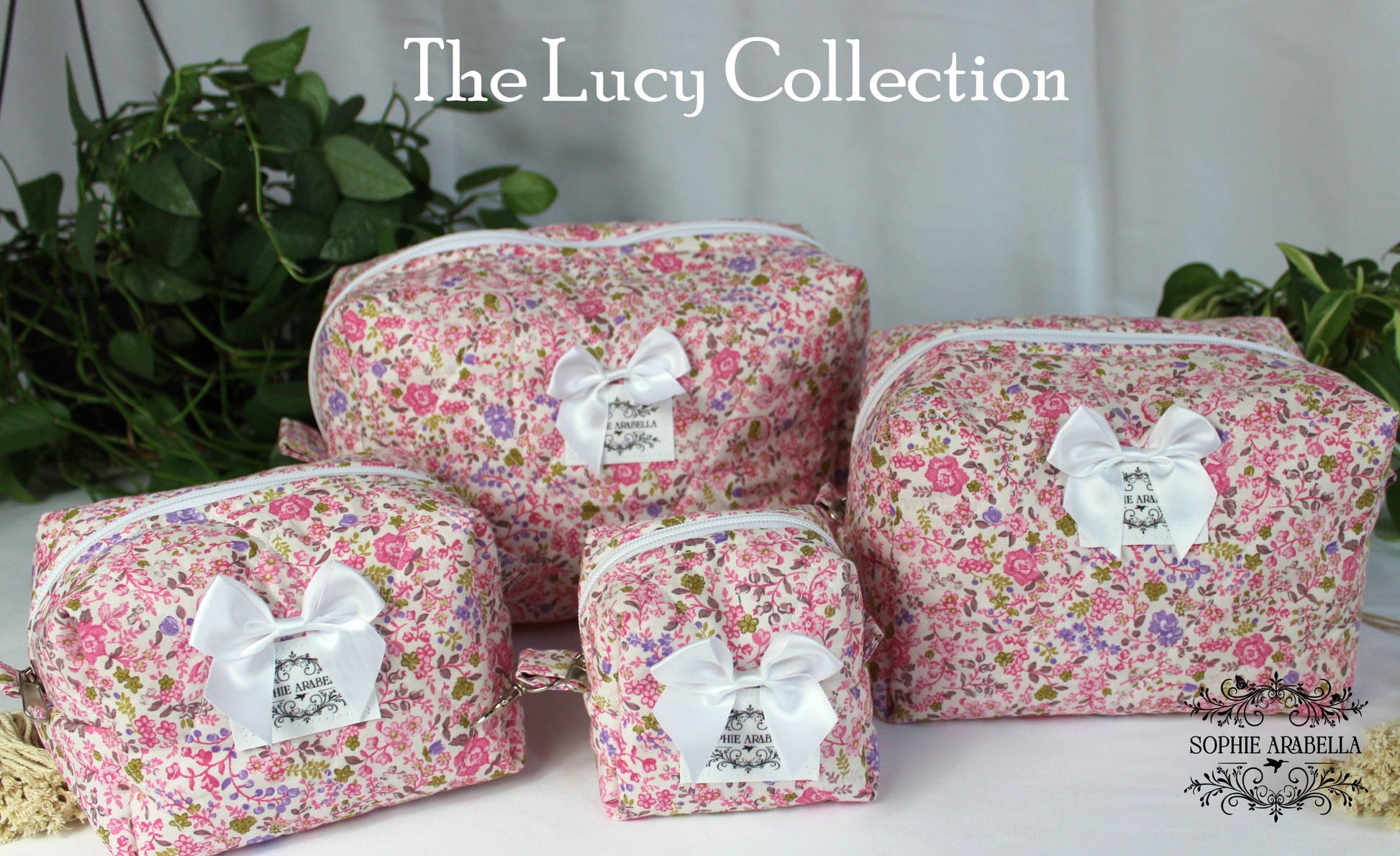 Set of floral makeup bags with white ribbons labeled 'The Lucy Collection' on a neutral background.