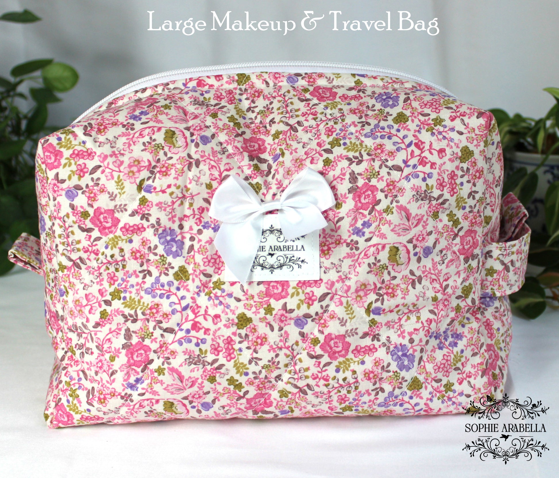 Floral patterned makeup and travel bag with a white bow on a light background